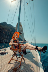 Happy beautiful woman on the luxury yacht sitting in chair.