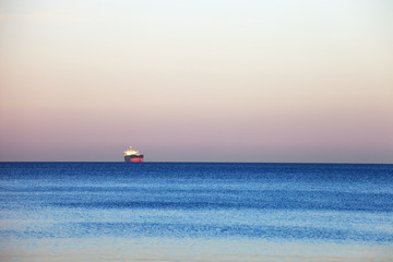 Small lonely ship floating on flat surface of sea on calm morning. © Nightman1965