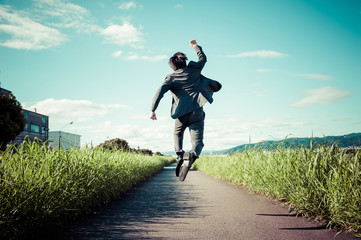 Fototapeta 道路でジャンプをするスーツのビジネスマン obraz