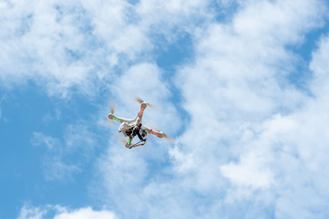 white drone hovering in a bright blue sky