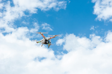 white drone hovering in a bright blue sky