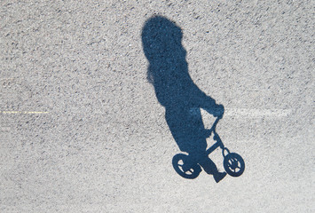 Shadow of a toddler riding a balance bike.