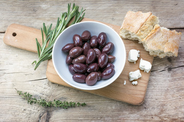 Kalamata black olives, bread, feta cheese and herbs on rustic wo