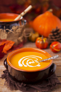 Homemade pumpkin soup on a rustic table with autumn decorations