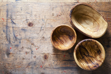 Three wooden bowls from olive tree on a wooden background