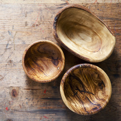 Three wooden bowls from olive tree on a wooden background