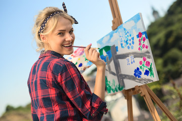 Beautiful blonde woman artist paints a colorful picture.