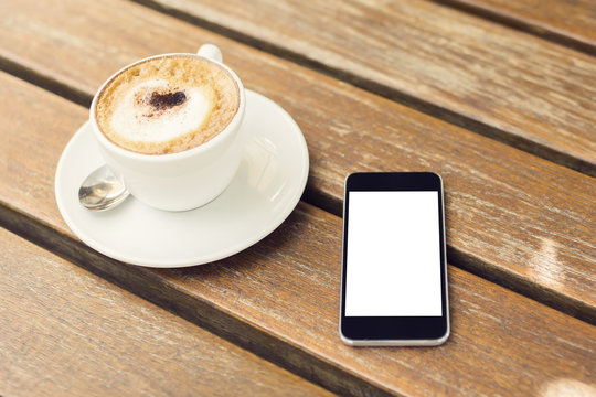 blank cell phone and cup of coffee on a wooden table