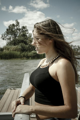 Fototapeta premium Chica adolescente posando en el embarcadero. Adolescente rubia de quince años como modelo. Chica rubia de pelo largo al lado del rio en verano.