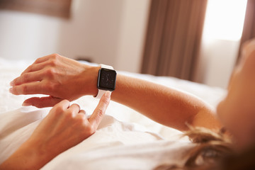 Woman Lying in Bed Whislt Checking The Time on Smart Watch