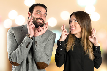 Couple with their fingers crossing over white background
