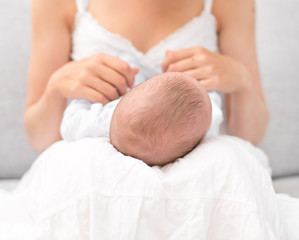 Obraz na płótnie Canvas Mother is holding newborn baby on her knees.