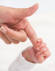 Newborn baby holding mother's hand.