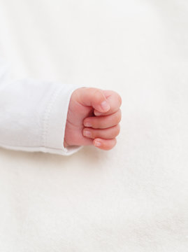 Little hand of newborn baby on the blanket.