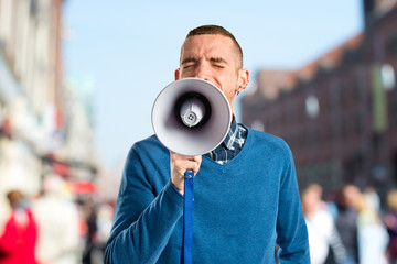 Redhead man shouting by megaphone over white background