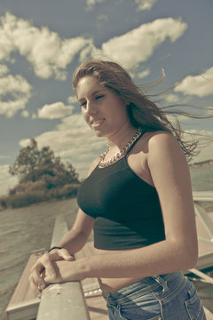 Chica adolescente posando en el embarcadero. Adolescente rubia de quince años como modelo. Chica rubia de pelo largo al lado del rio en verano. Proceso Cruzado Retro.