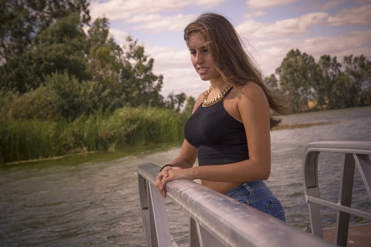 Chica adolescente posando en el embarcadero. Adolescente rubia de quince años como modelo. Chica rubia de pelo largo al lado del rio en verano.