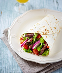 A fajita filled with grilled pork and fresh vegetables
