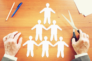 Team building concept. Abstract conceptual image with a man cutting human characters on the table