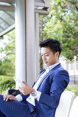 Fototapeta premium ベンチに座ってスマホを見るビジネスマン