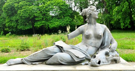Bronze statue depicting nude woman with book and skull