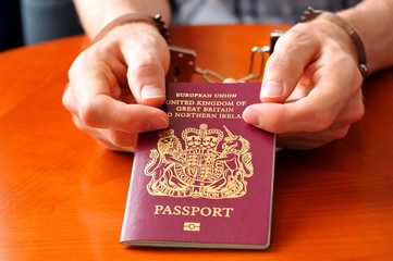 Illegal immigration concept with hands holding UK passport - obrazy, fototapety, plakaty