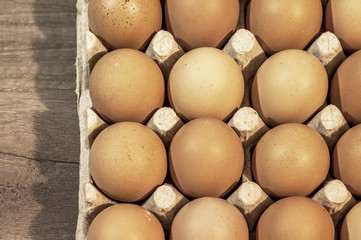 Eggs in carton package on a wooden table ready for cooking