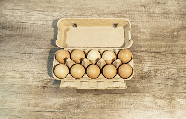 Eggs, ten brown eggs in a carton package on a wooden table
