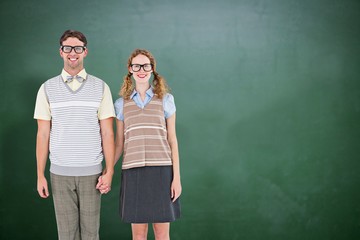 Composite image of smiling geeky hipster couple holding hands 