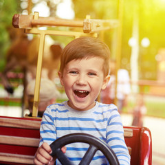 boy driving a car on merry-go-round