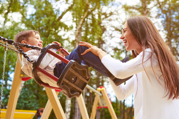 happy mother pushing laughing son