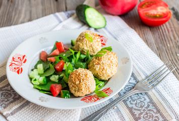 baked chickpeas balls with sesame and vegetable salad on a gray