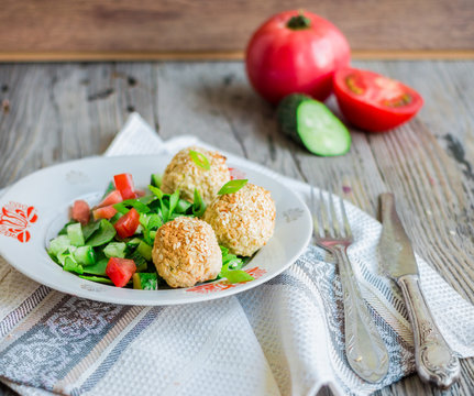 baked chickpeas balls with sesame and vegetable salad on a gray