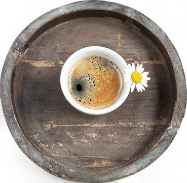 Tasse Kaffee mit Blümchen auf rundem Tablett