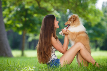 Beautiful woman playing in the park with a small puppy collie