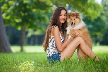 Beautiful woman playing in the park with a small puppy collie