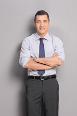 Young businessman leaning against a gray wall