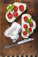 Bruschetta with soft cheese, basil and cherry tomatoes on a wood