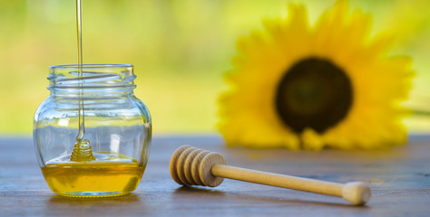 Honey dripping off a honey spoon into a glass bowl.