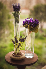 Vases with purple flowers on small table