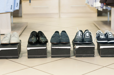 Men's shoes on black boxes in a store.