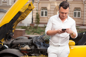 Driver man using smartphone near damaged car