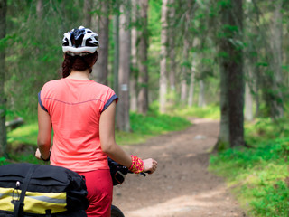 Woman riding a bike on the forest trail in sunny day