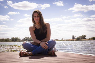 Chica adolescente posando en el embarcadero. Adolescente rubia de quince años como modelo. Chica rubia de pelo largo al lado del rio en verano.