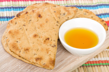Flatbread - Middle Eastern multi seeded flatbread served with olive oil on a colourful background.