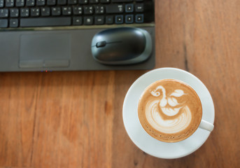 Cafe latte with latte art on working desk soft focus background