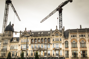 Fototapeta na wymiar A row of historical buildings in Antwerp, Belgium with cranes in the background 
