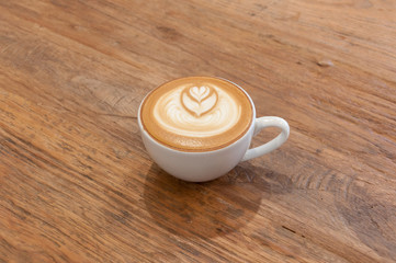 Hot cafe latte wirh latte art on wooden table