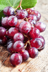 Round purple grapes with leaves on the old wooden table, selecti