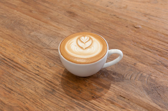Hot cafe latte wirh latte art on wooden table